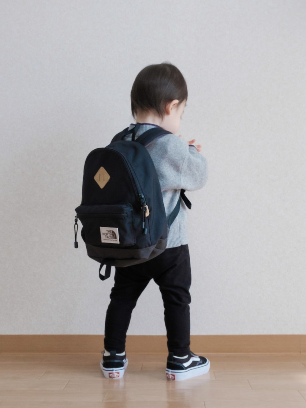 グレー系のニット/セーター、ブラック系のバックパック/リュック、ブラック系のスウェットパンツを着用したキッズの春コーディネートの2枚目の写真