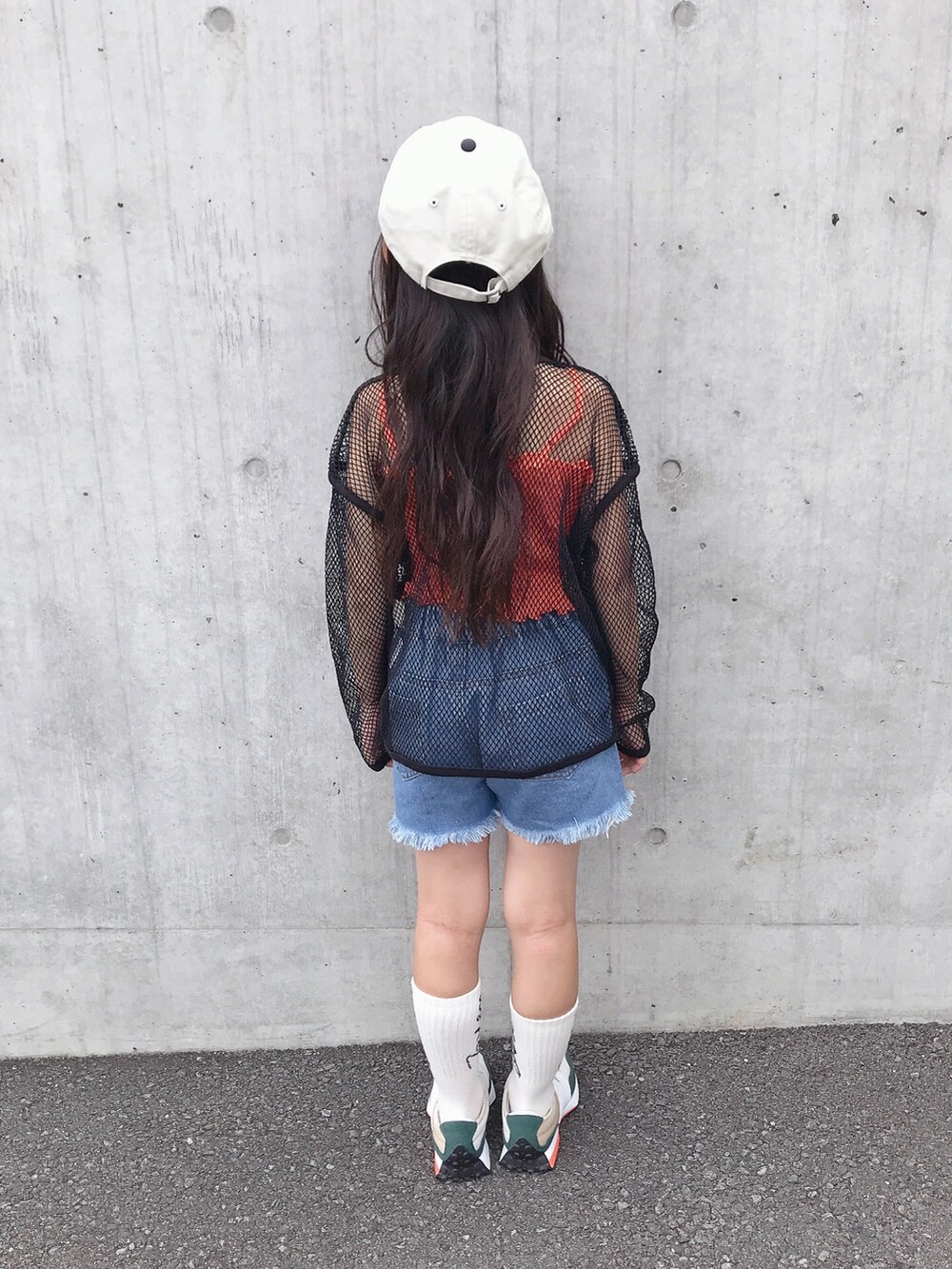 オレンジ系のキャミソール、グリーン系のスニーカー、ホワイト系のキャップを着用したキッズの夏コーディネートの3枚目の写真