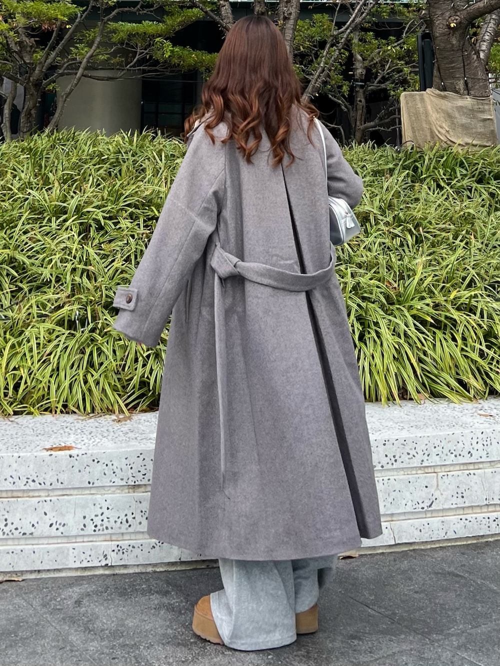 ブラウン系のブーツ、グレー系のその他パンツ、グレー系のステンカラーコートを着用したレディースの冬コーディネートの2枚目の写真