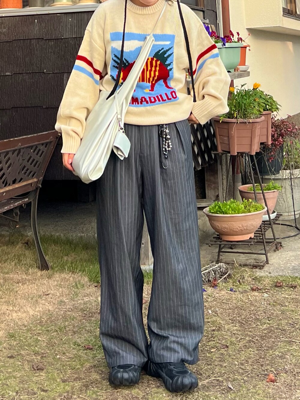 ブラック系のスニーカー、グレー系のスラックス、シルバー系のショルダーバッグを着用したレディースの冬コーディネートの3枚目の写真