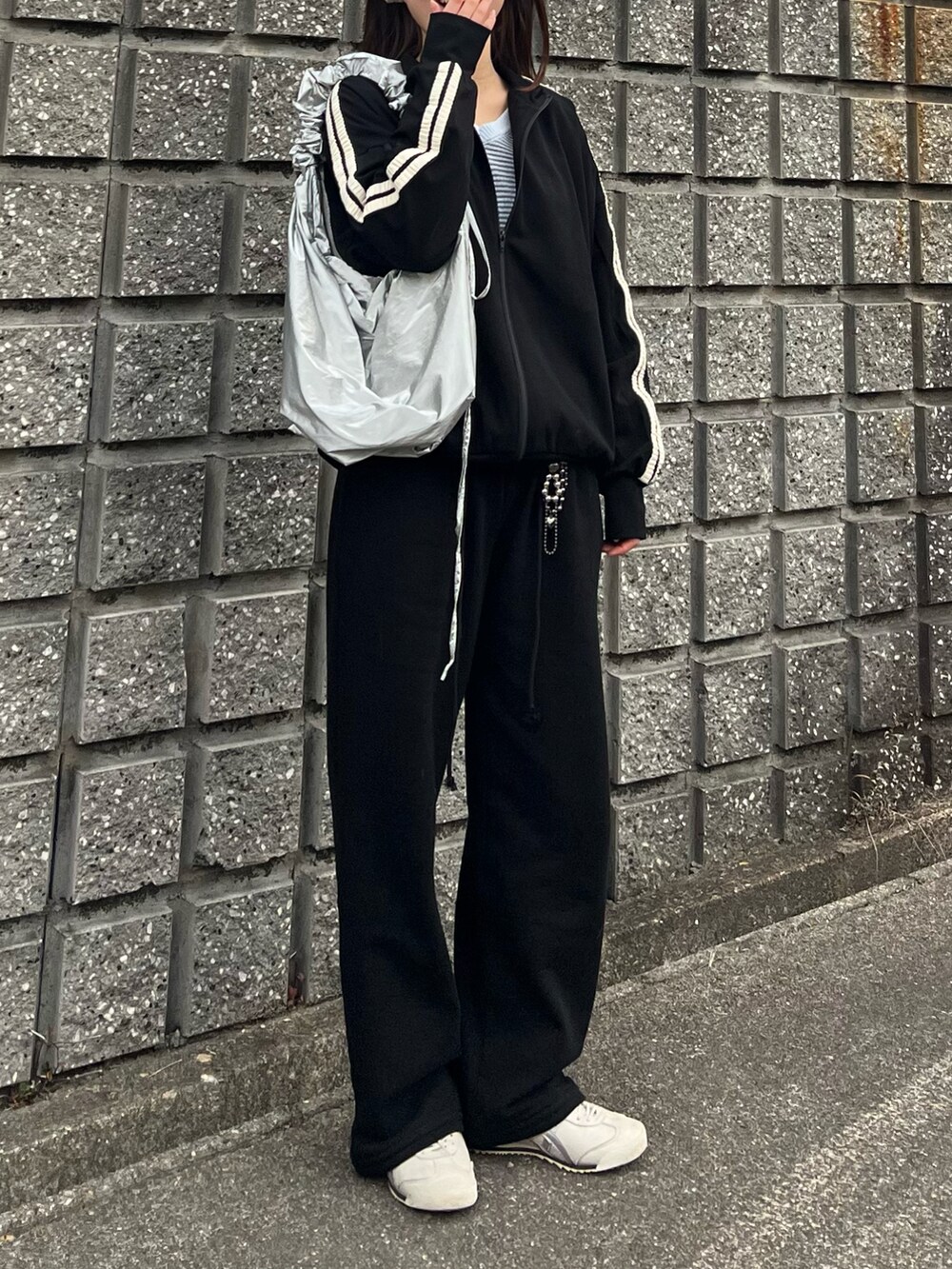 ホワイト系のスニーカー、ブラック系のスウェットパンツ、シルバー系のショルダーバッグを着用したレディースの冬コーディネートの2枚目の写真