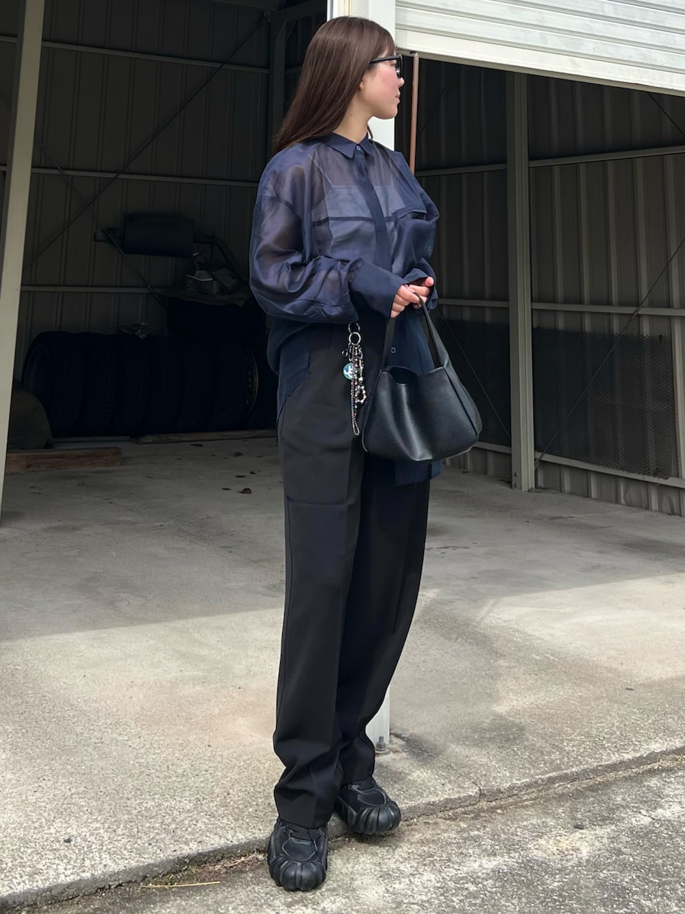 ブラック系のハンドバッグ、ブラック系のスニーカー、ブラック系のスラックスを着用したレディースの春コーディネートの3枚目の写真