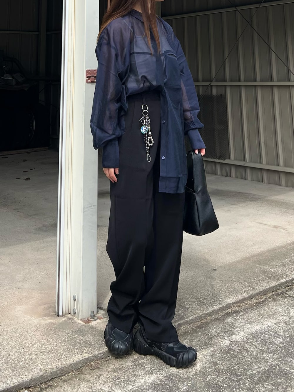 ブラック系のハンドバッグ、ブラック系のスニーカー、ブラック系のスラックスを着用したレディースの春コーディネートの5枚目の写真