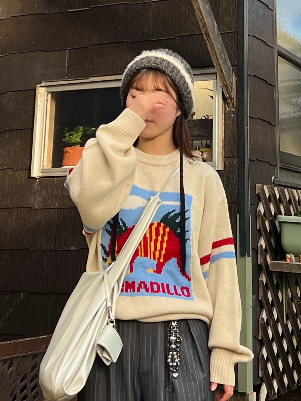 ブラック系のスニーカー、グレー系のスラックス、シルバー系のショルダーバッグを着用したレディースの冬コーディネートの2枚目の写真