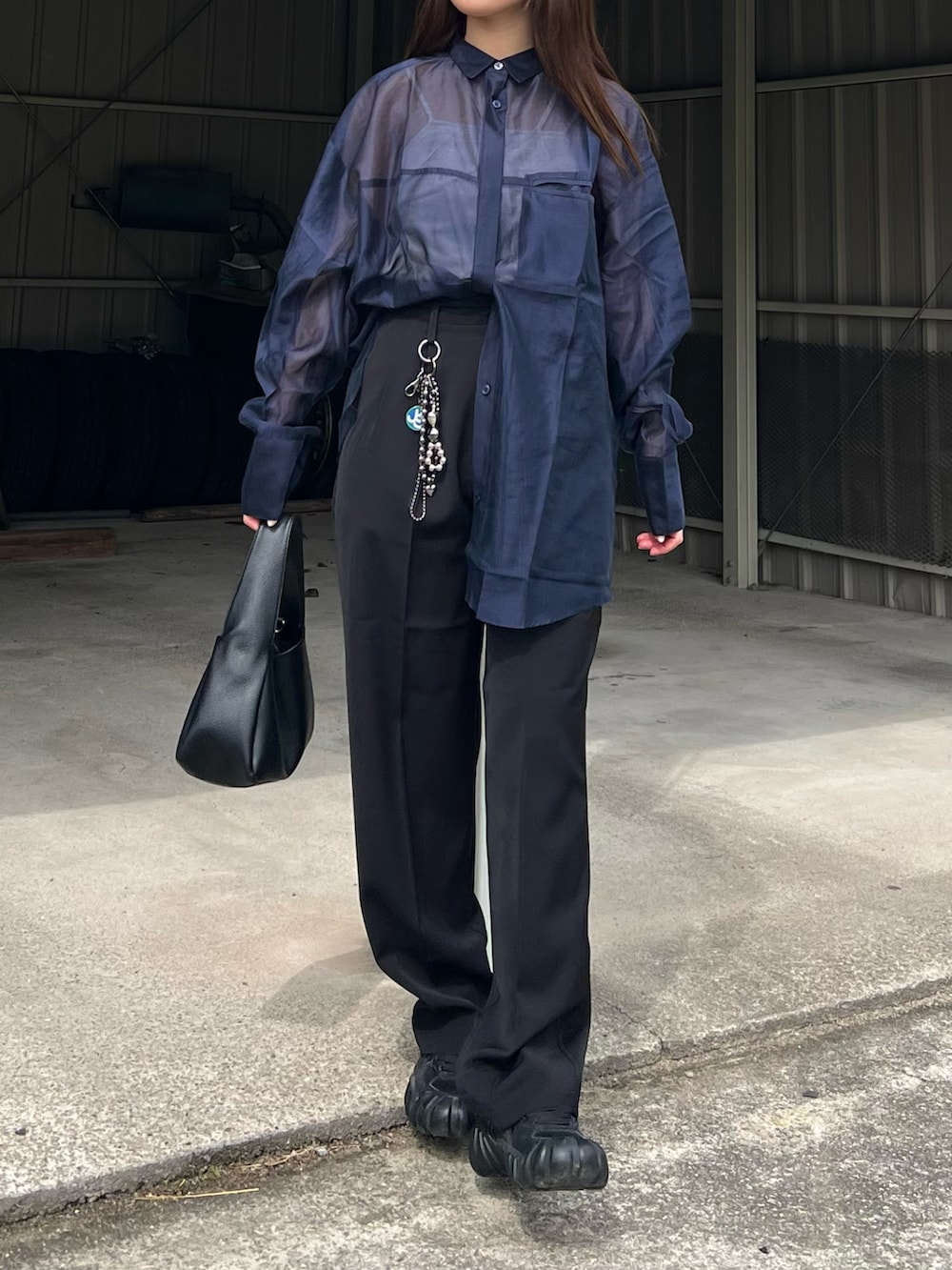 ブラック系のハンドバッグ、ブラック系のスニーカー、ブラック系のスラックスを着用したレディースの春コーディネートの2枚目の写真