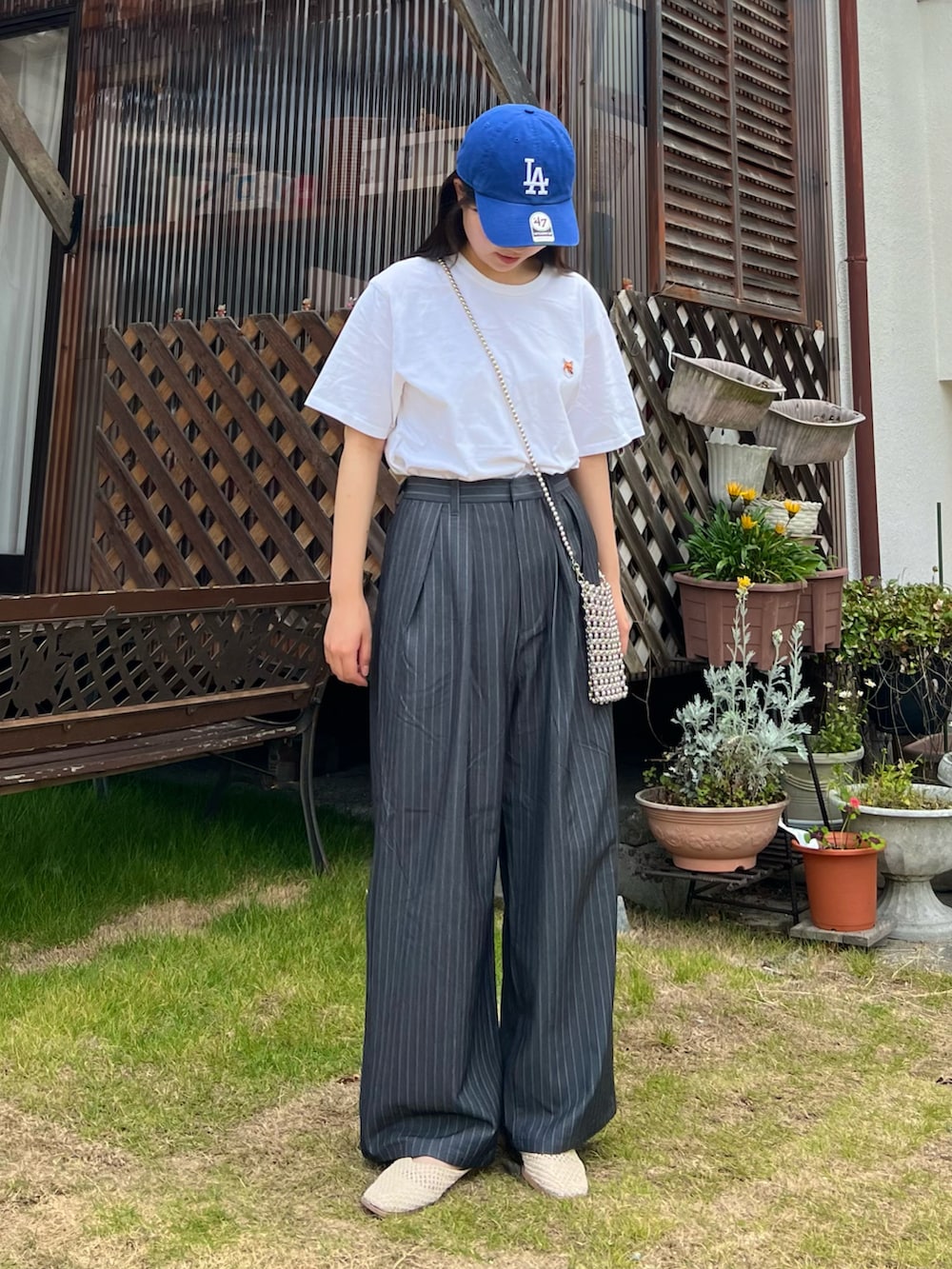 グレー系のスラックス、ホワイト系のスリッポン、シルバー系のショルダーバッグを着用したレディースの夏コーディネートの3枚目の写真