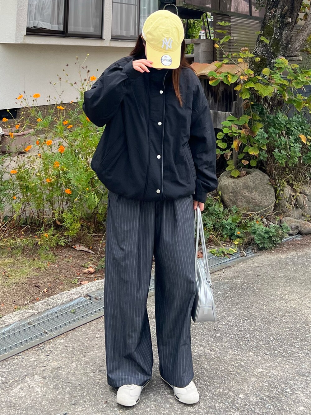 ホワイト系のスニーカー、グレー系のスラックス、シルバー系のボストンバッグを着用したレディースの秋コーディネートの2枚目の写真