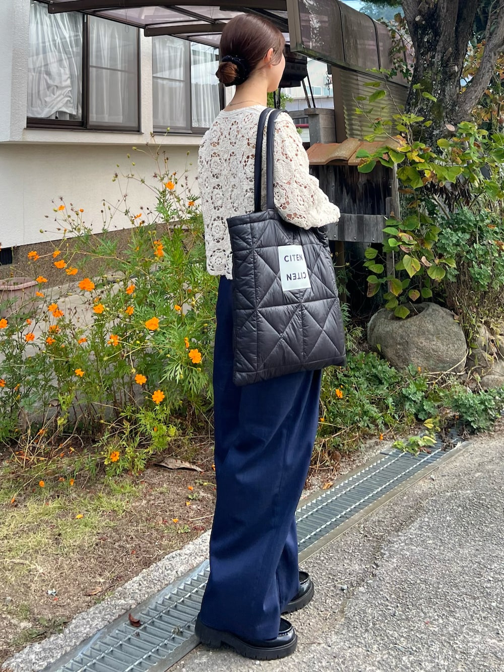 ブラック系のローファー、ブルー系のスラックス、ブラック系のトートバッグを着用したレディースの秋コーディネートの2枚目の写真