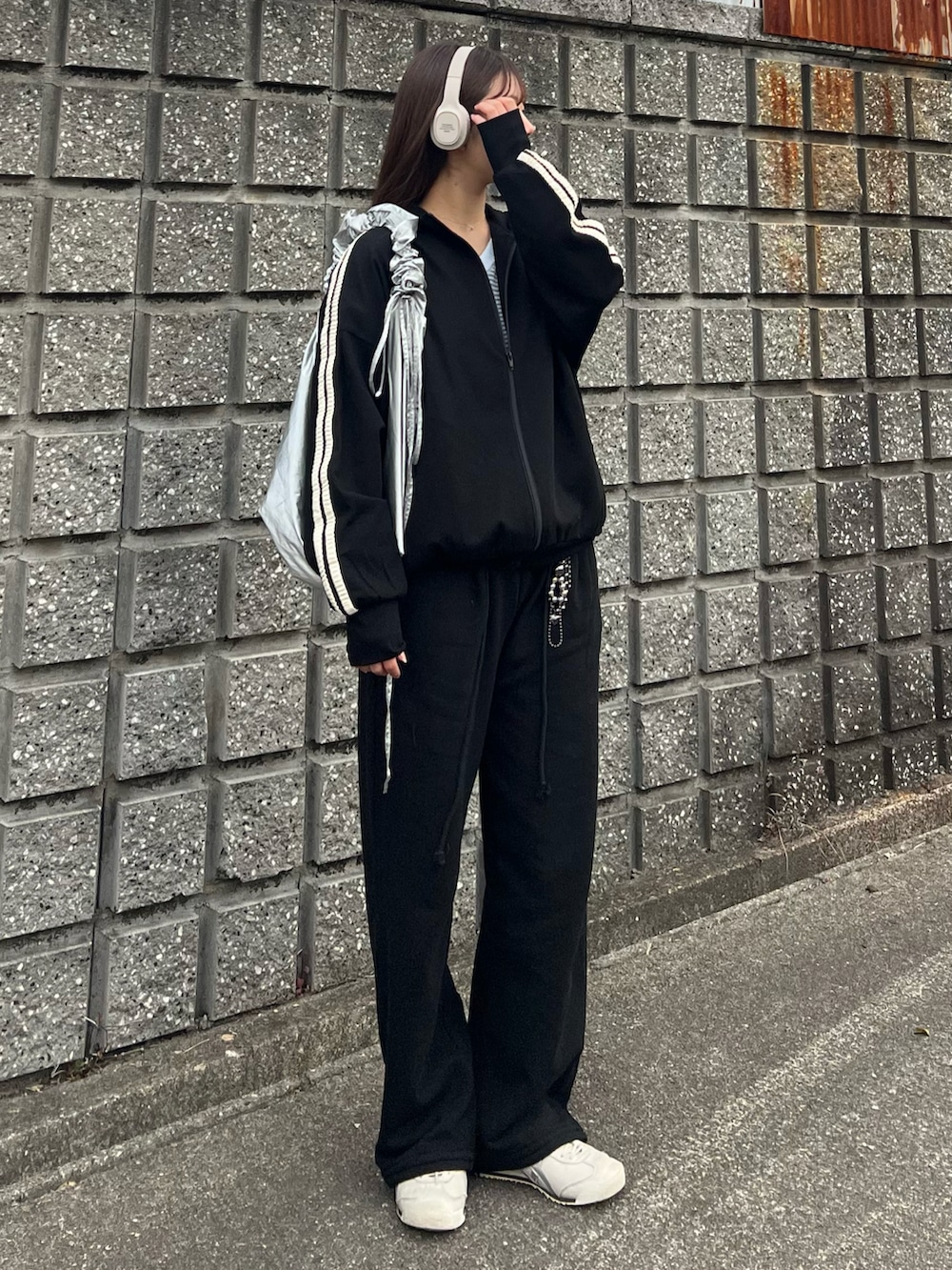 ホワイト系のスニーカー、ブラック系のスウェットパンツ、シルバー系のショルダーバッグを着用したレディースの冬コーディネートの5枚目の写真