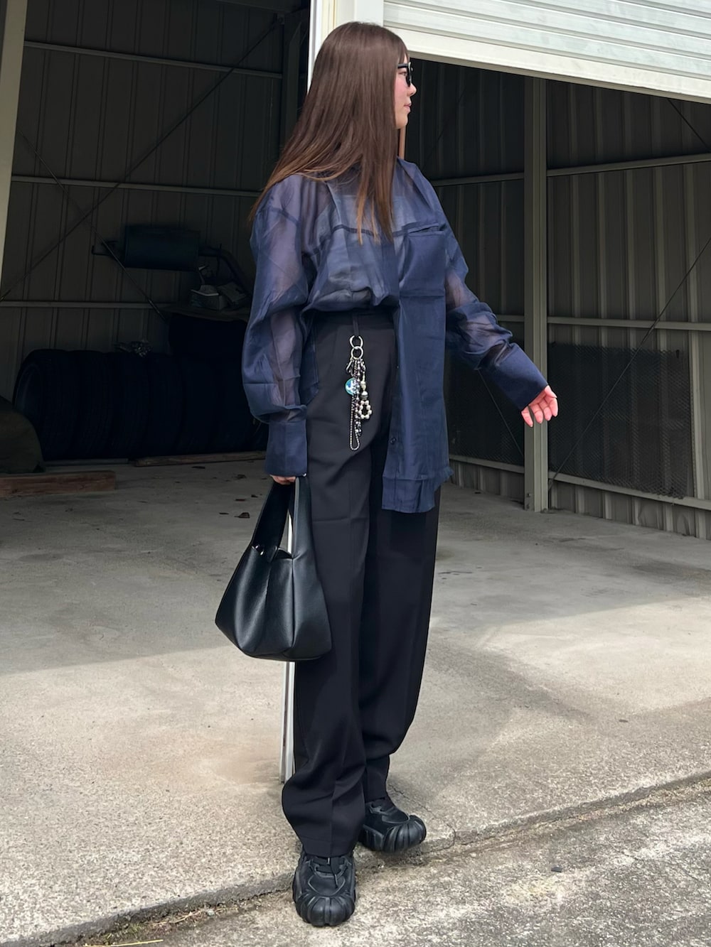 ブラック系のハンドバッグ、ブラック系のスニーカー、ブラック系のスラックスを着用したレディースの春コーディネートの4枚目の写真