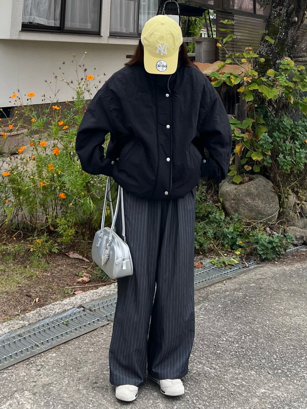 ホワイト系のスニーカー、グレー系のスラックス、シルバー系のボストンバッグを着用したレディースの秋コーディネートの3枚目の写真