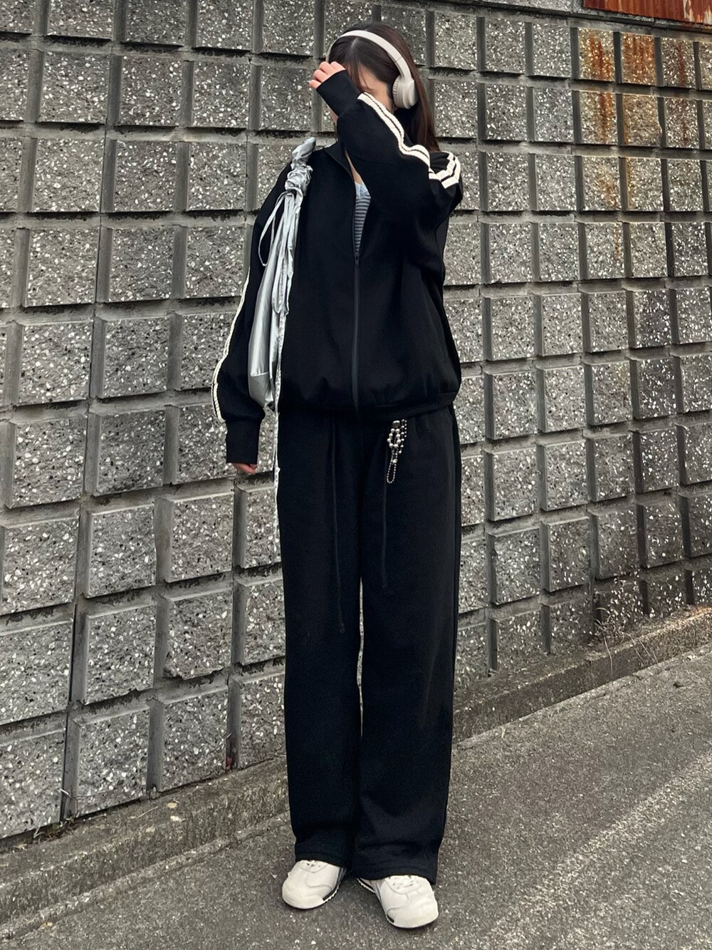 ホワイト系のスニーカー、ブラック系のスウェットパンツ、シルバー系のショルダーバッグを着用したレディースの冬コーディネートの3枚目の写真