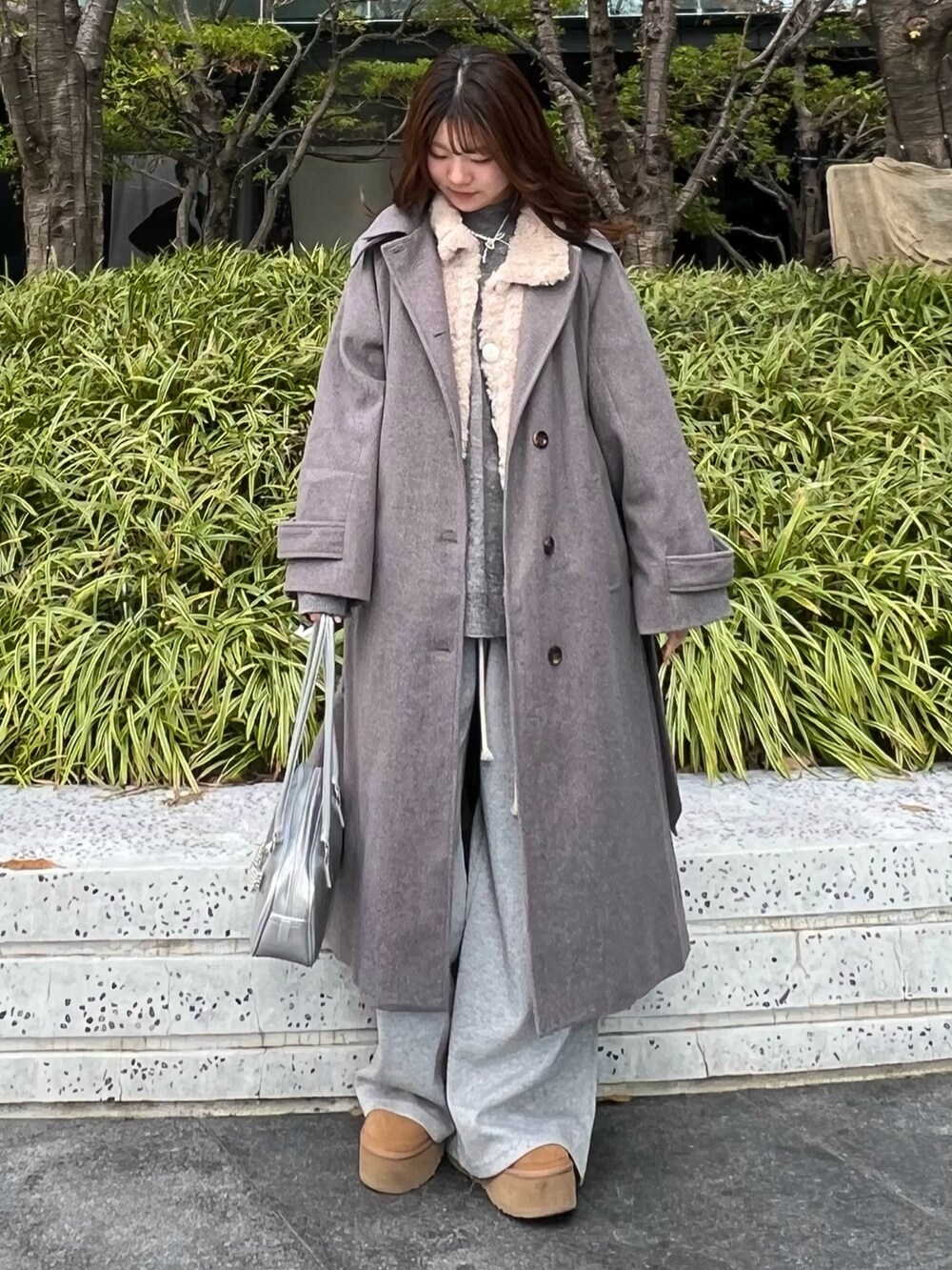 ブラウン系のブーツ、グレー系のその他パンツ、グレー系のステンカラーコートを着用したレディースの冬コーディネートの3枚目の写真