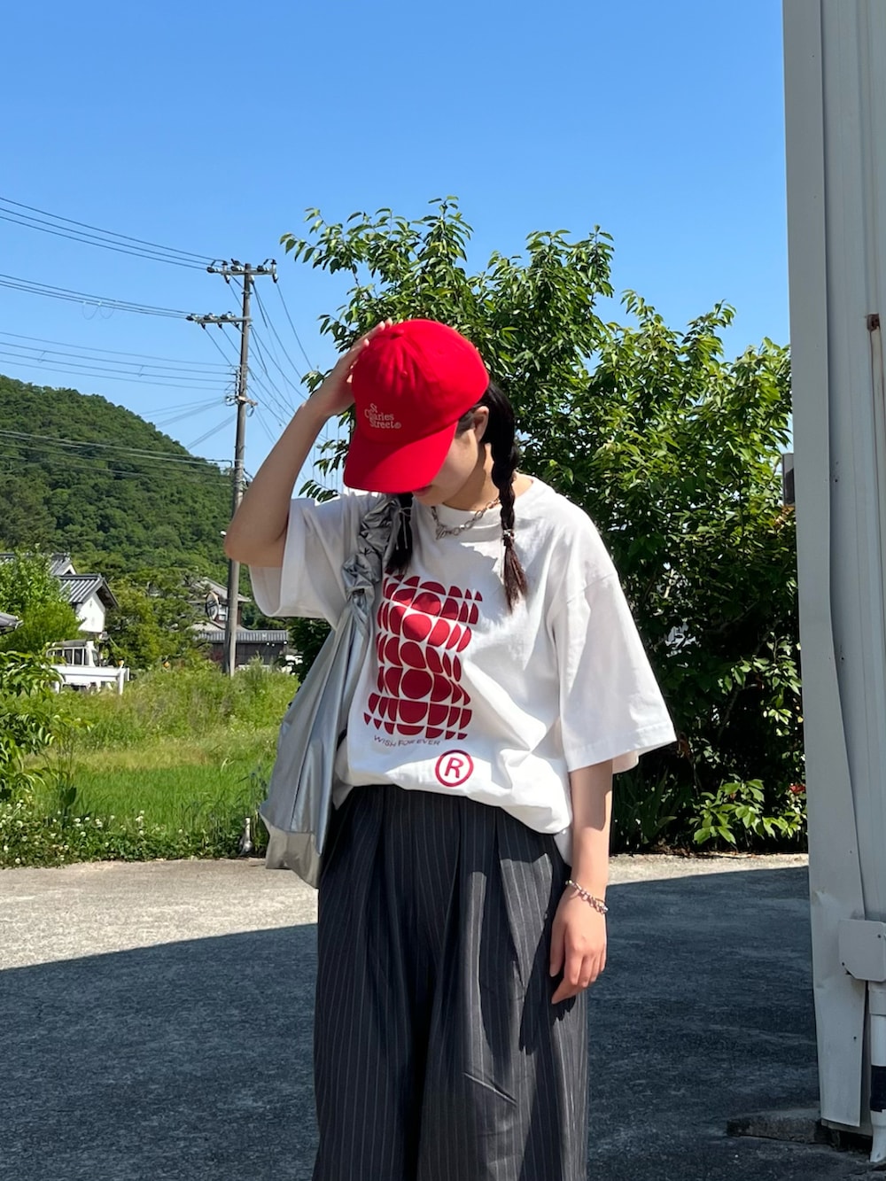 グレー系のスラックス、ブラック系のスニーカー、ホワイト系のTシャツ/カットソーを着用したレディースの夏コーディネートの3枚目の写真