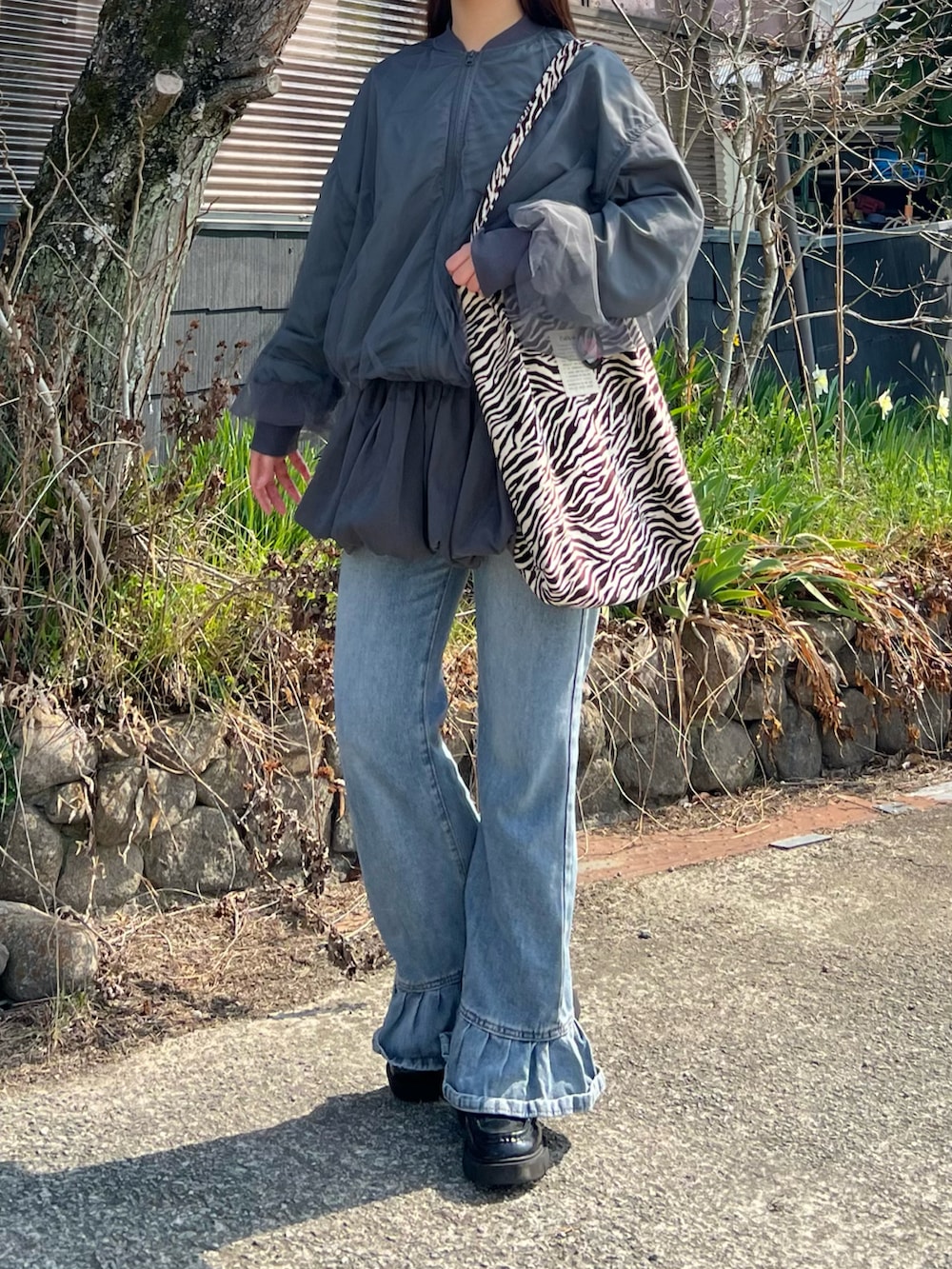 ブラック系のローファー、ブルー系のデニムパンツ、その他のトートバッグを着用したレディースの春コーディネートの2枚目の写真