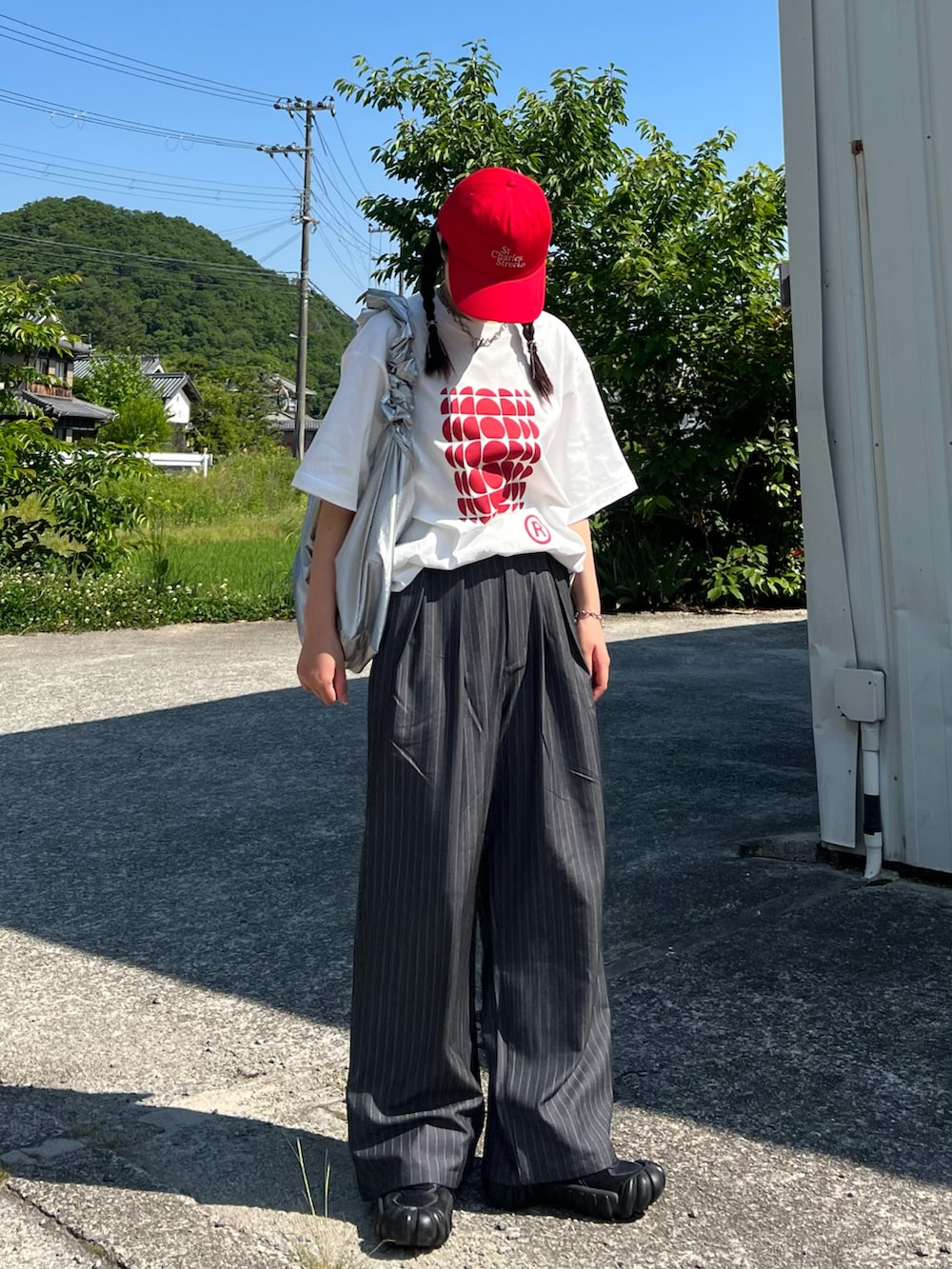 グレー系のスラックス、ブラック系のスニーカー、ホワイト系のTシャツ/カットソーを着用したレディースの夏コーディネートの2枚目の写真