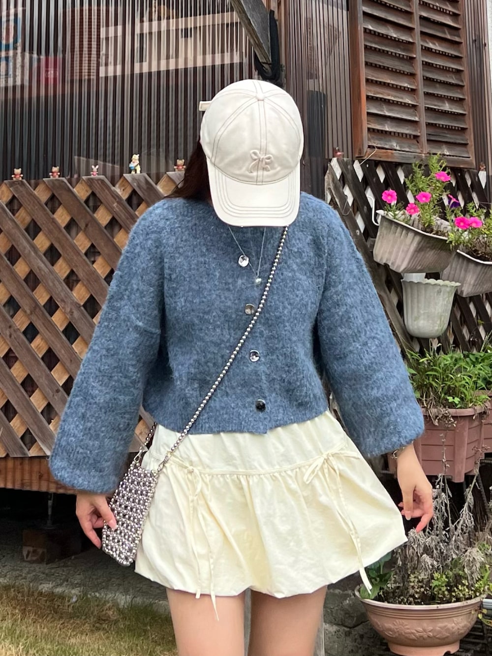 シルバー系のショルダーバッグ、ブルー系のカーディガン/ボレロ、ホワイト系のスニーカーを着用したレディースの秋コーディネートの2枚目の写真