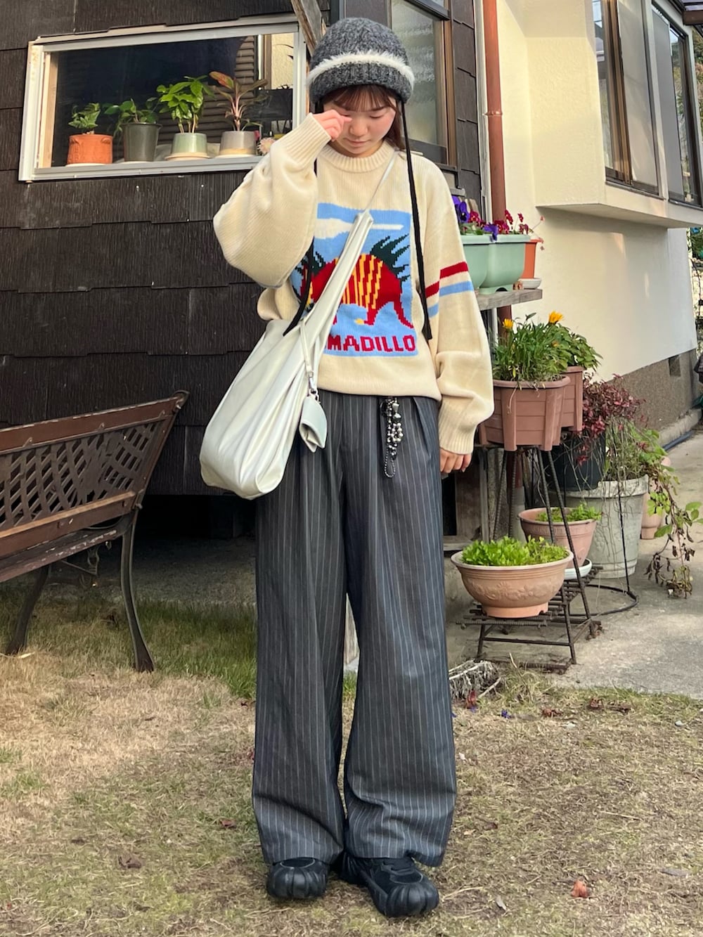 ブラック系のスニーカー、グレー系のスラックス、シルバー系のショルダーバッグを着用したレディースの冬コーディネートの4枚目の写真