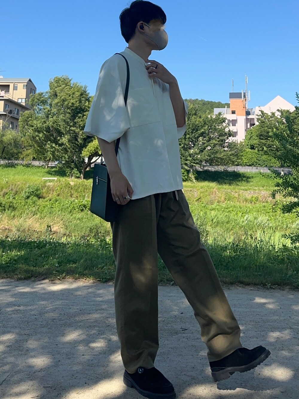 グリーン系のスラックス、グリーン系のショルダーバッグ、ホワイト系のシャツ/ブラウスを着用したメンズの夏コーディネートの2枚目の写真