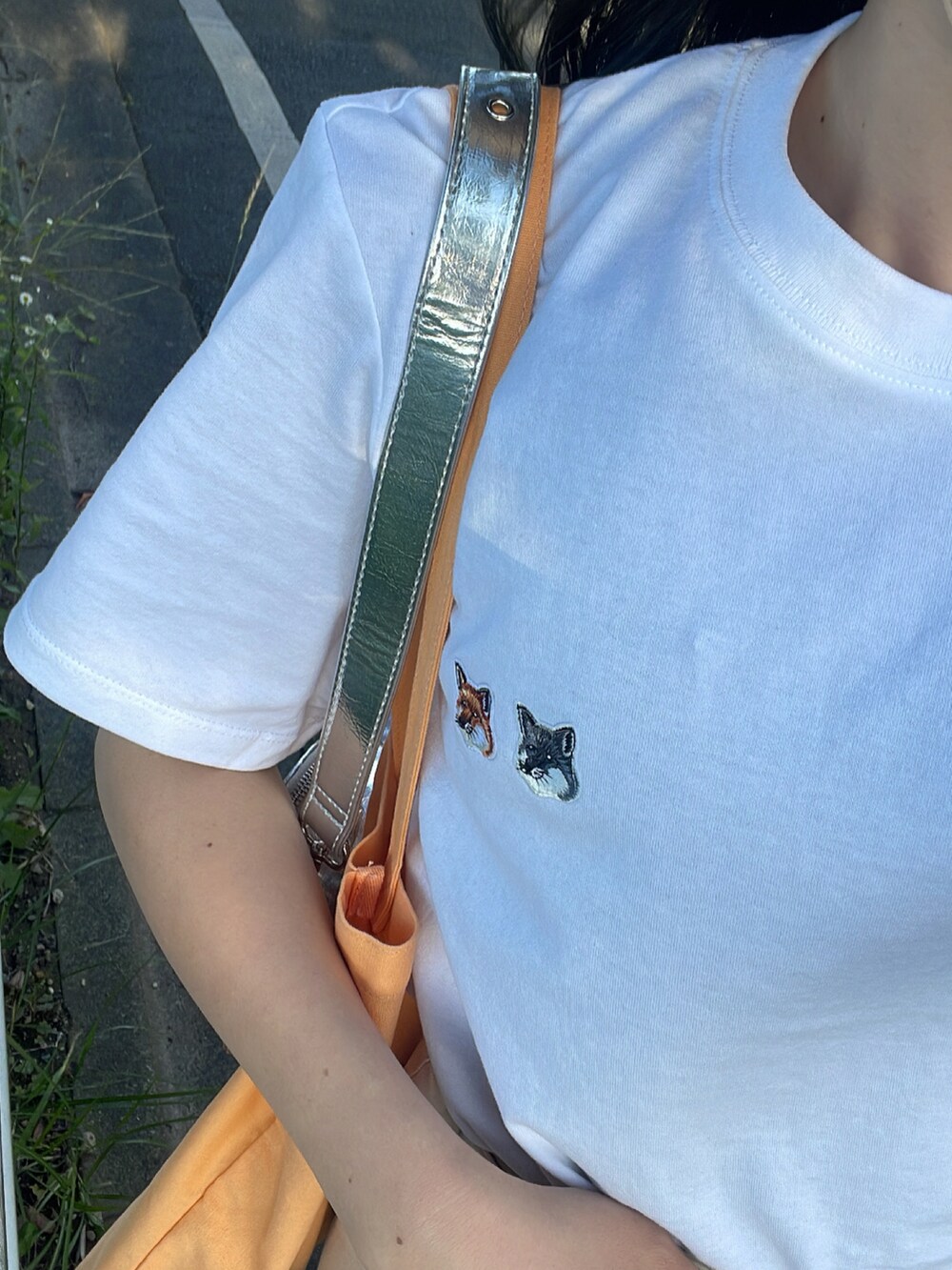 オレンジ系のトートバッグ、シルバー系のショルダーバッグ、ホワイト系のTシャツ/カットソーを着用したレディースの夏コーディネートの4枚目の写真