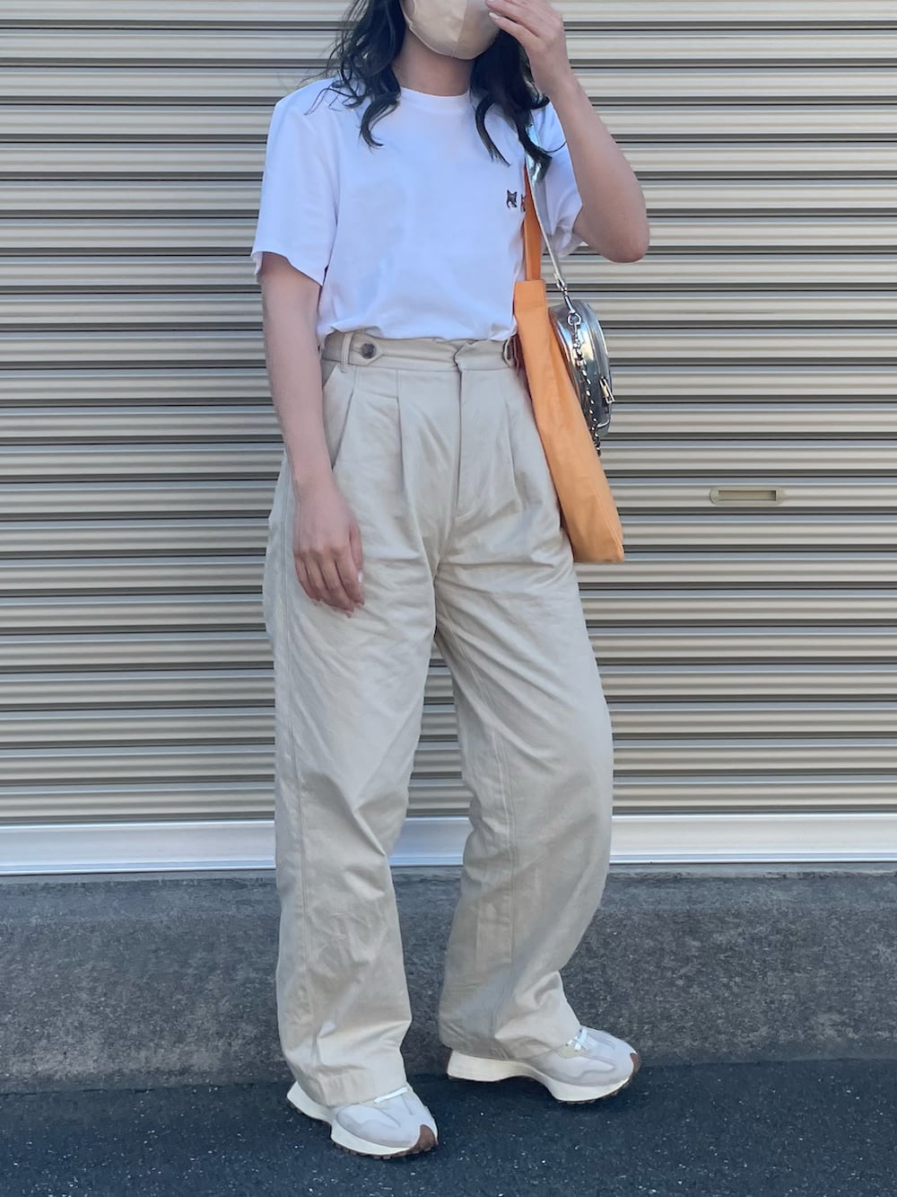 オレンジ系のトートバッグ、シルバー系のショルダーバッグ、ホワイト系のTシャツ/カットソーを着用したレディースの夏コーディネートの3枚目の写真