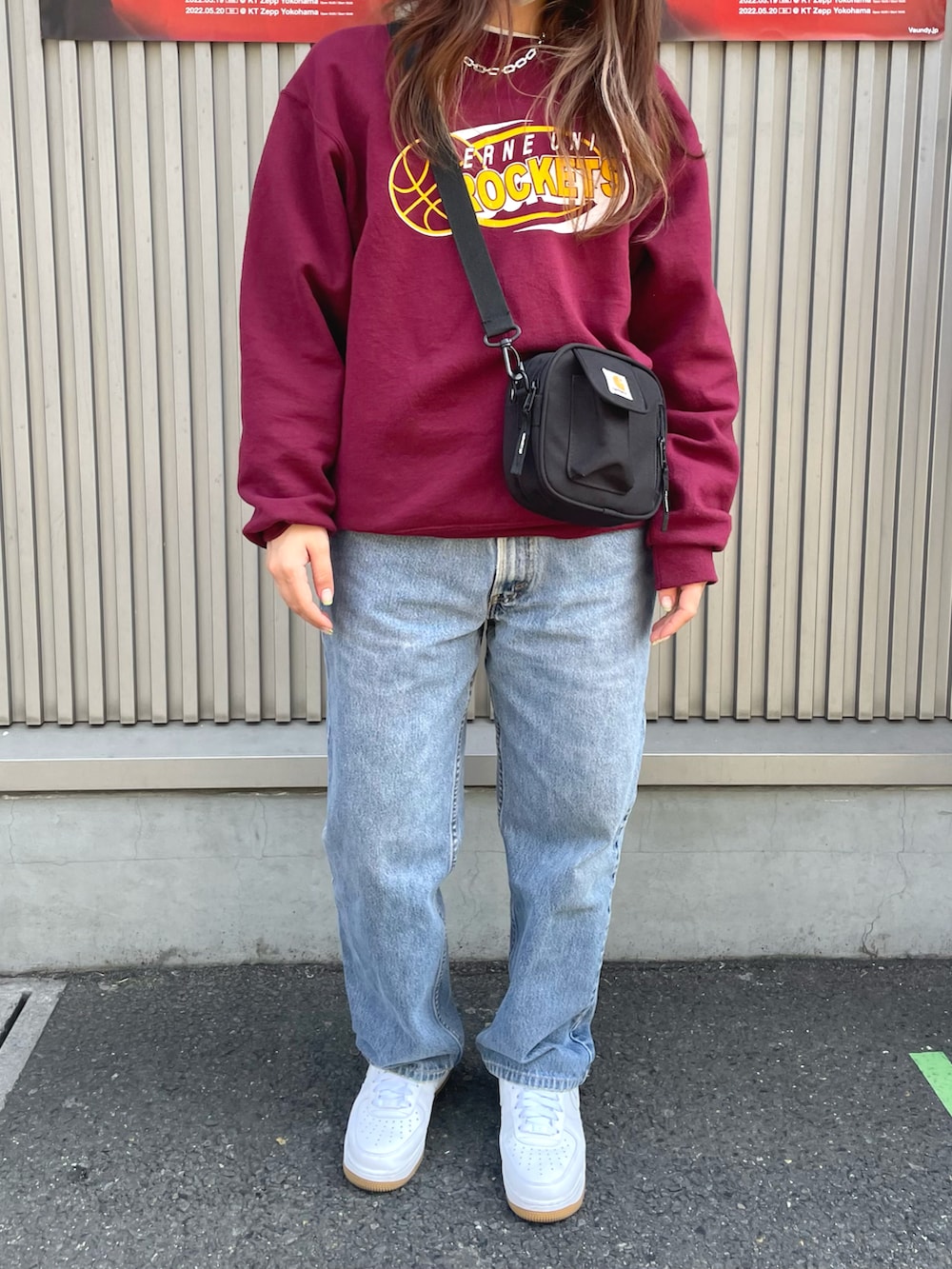 レッド系のスウェット、ブルー系のデニムパンツ、ホワイト系のスニーカーを着用したレディースの春コーディネートの2枚目の写真