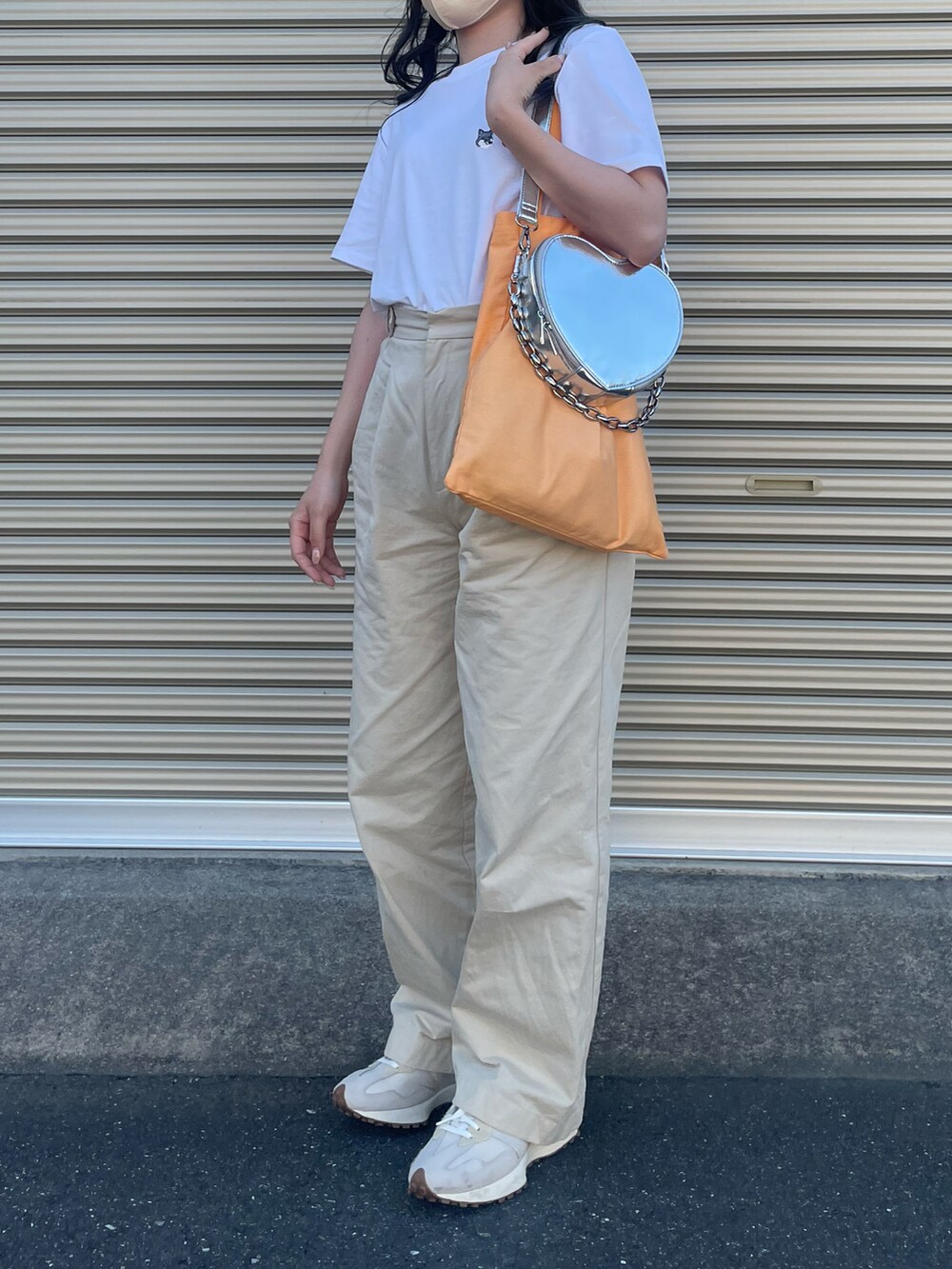 オレンジ系のトートバッグ、シルバー系のショルダーバッグ、ホワイト系のTシャツ/カットソーを着用したレディースの夏コーディネートの2枚目の写真