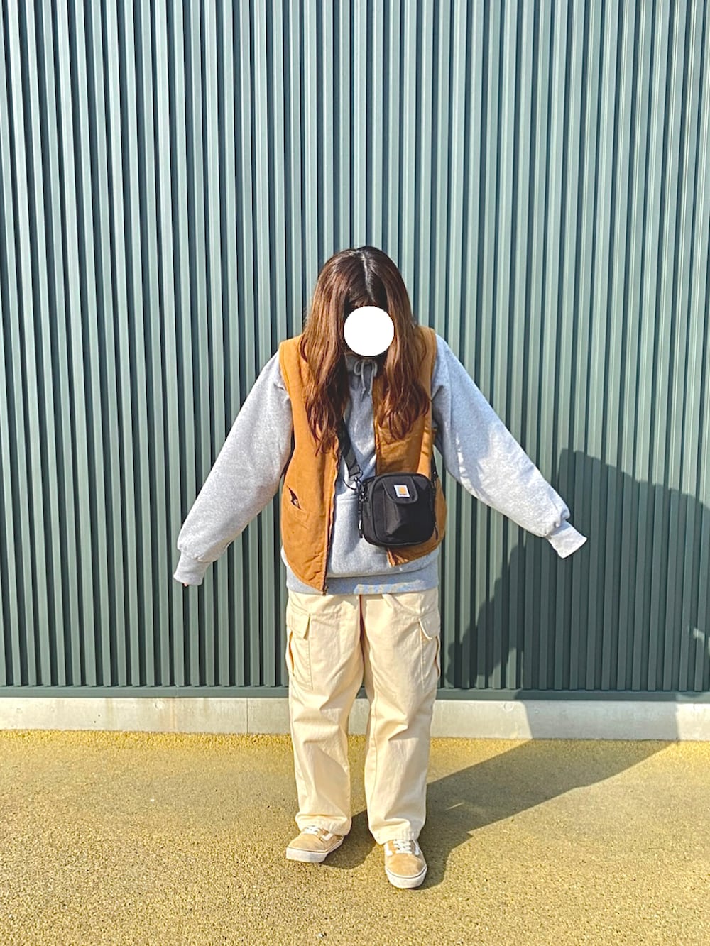 グレー系のパーカー、ブラウン系のベスト、ベージュ系のカーゴパンツを着用したレディースの冬コーディネートの2枚目の写真