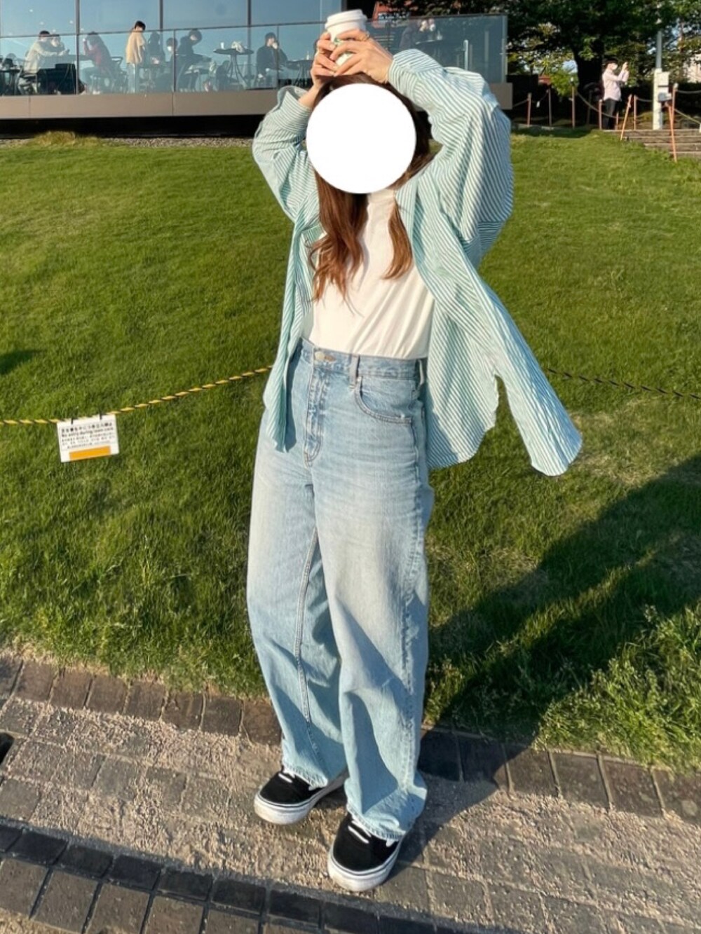 グリーン系のシャツ/ブラウス、ブラック系のスニーカー、ブルー系のデニムパンツを着用したレディースの春コーディネートの2枚目の写真