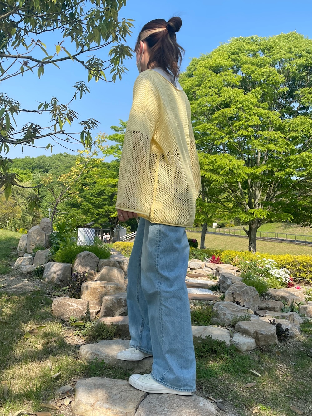 ブラック系のショルダーバッグ、イエロー系のトップス、ホワイト系のスニーカーを着用したレディースの春コーディネートの2枚目の写真