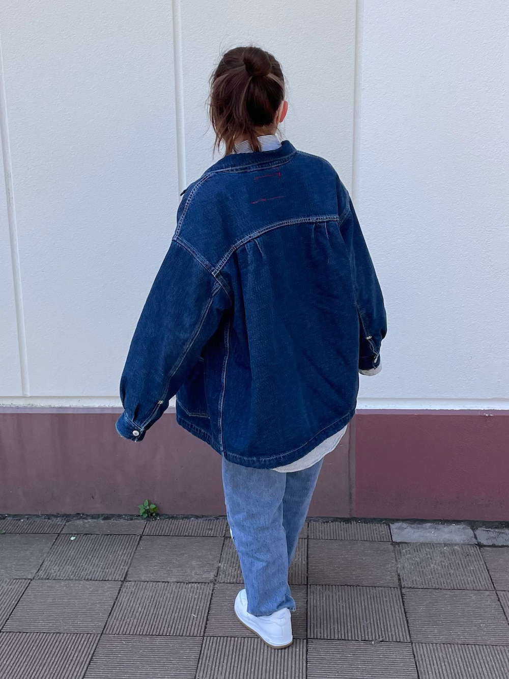 ブルー系のデニムジャケット、ホワイト系のスニーカー、グレー系のシャツ/ブラウスを着用したレディースの春コーディネートの2枚目の写真