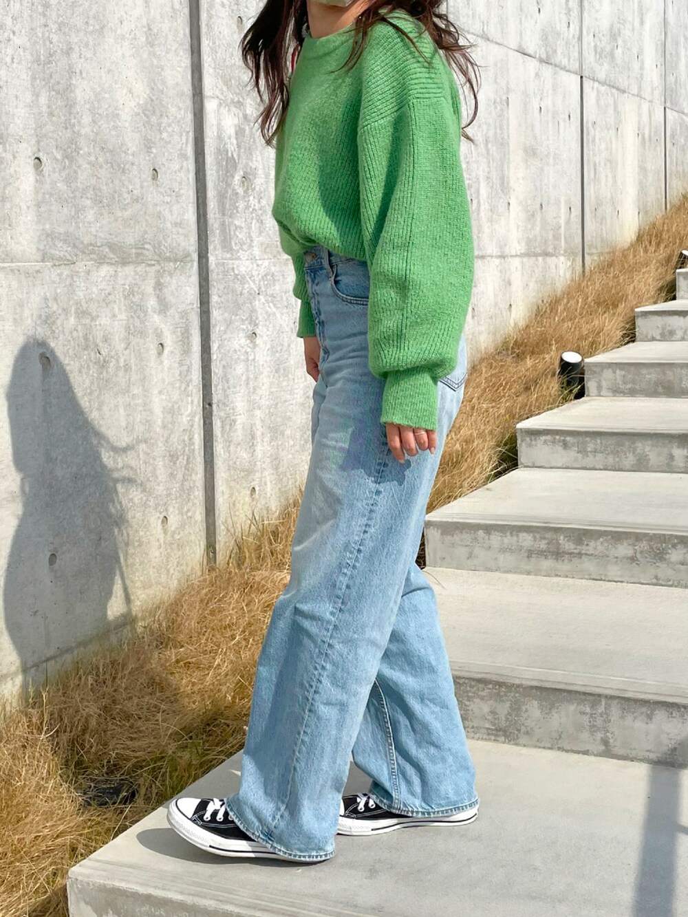 グリーン系のニット/セーター、ベージュ系のショルダーバッグ、ブラック系のスニーカーを着用したレディースの春コーディネートの2枚目の写真