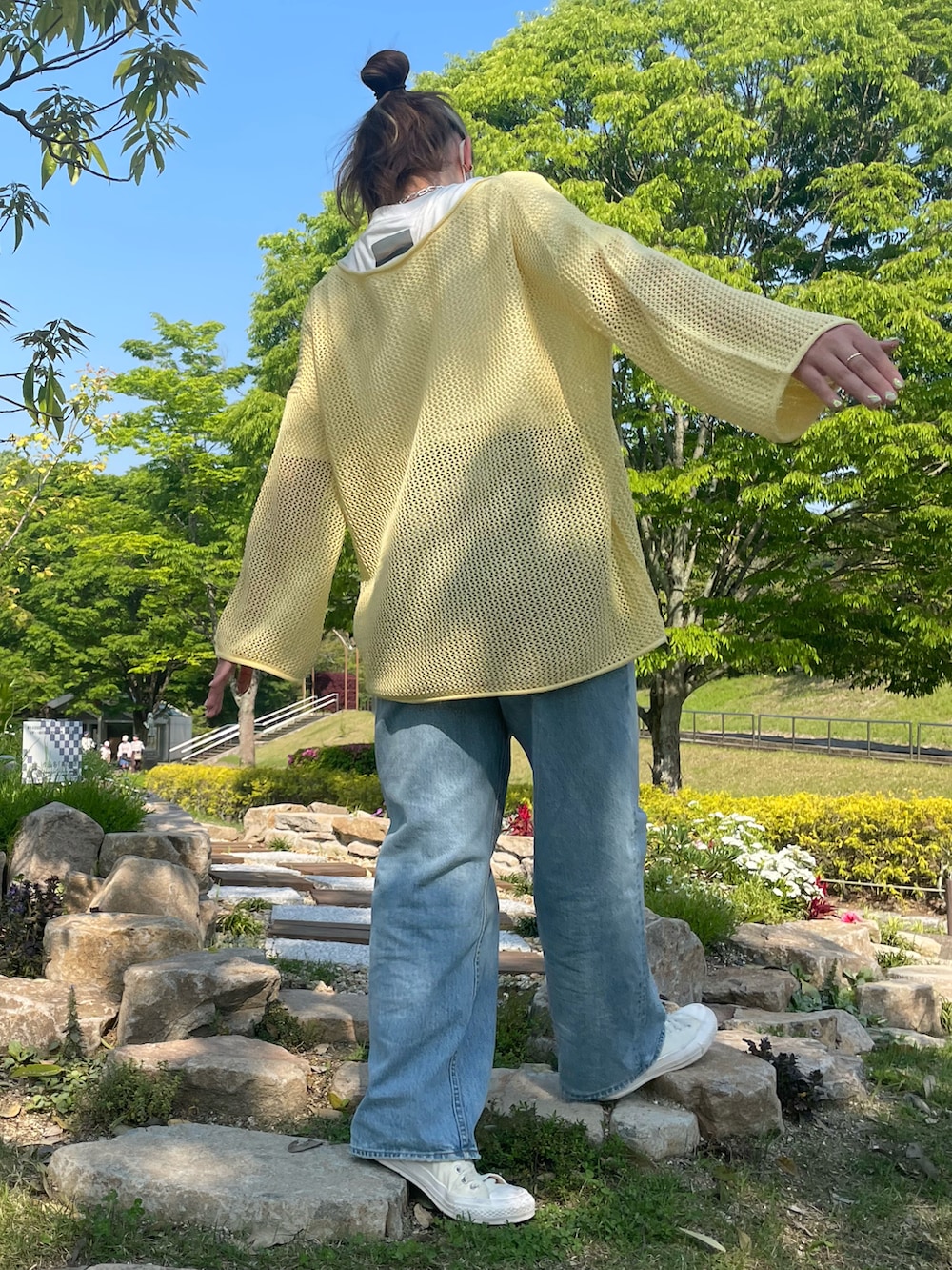 ブラック系のショルダーバッグ、イエロー系のトップス、ホワイト系のスニーカーを着用したレディースの春コーディネートの3枚目の写真