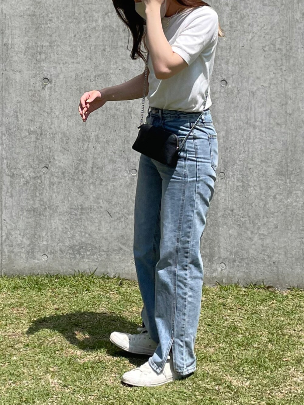 ホワイト系のニット/セーター、ブラック系のショルダーバッグ、ブルー系のデニムパンツを着用したレディースの春コーディネートの2枚目の写真