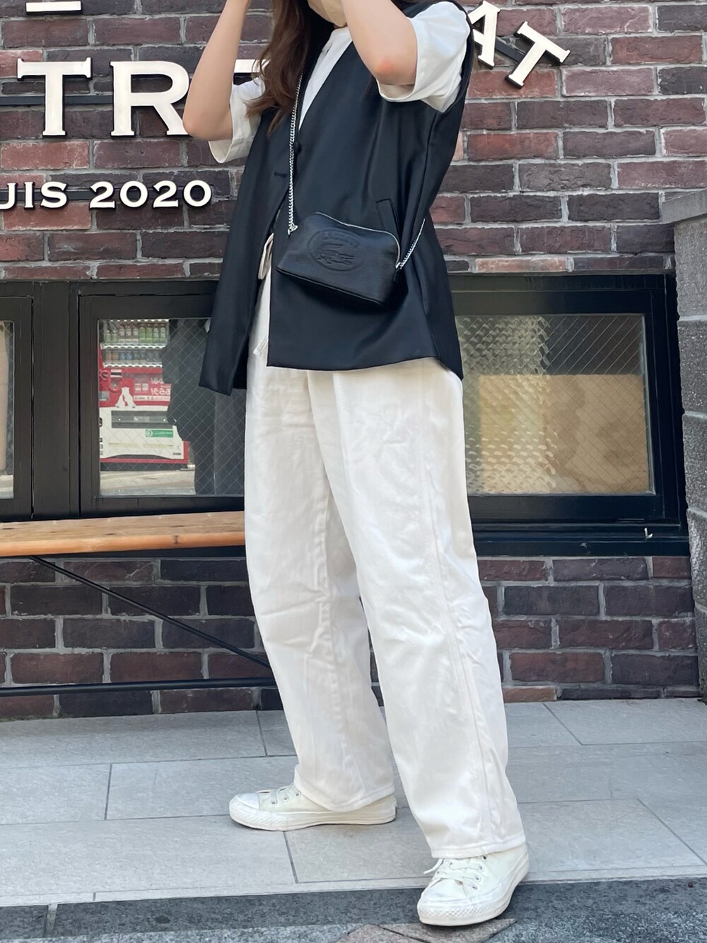 ブラック系のショルダーバッグ、ブラック系のベスト、ホワイト系のデニムパンツを着用したレディースの夏コーディネートの3枚目の写真