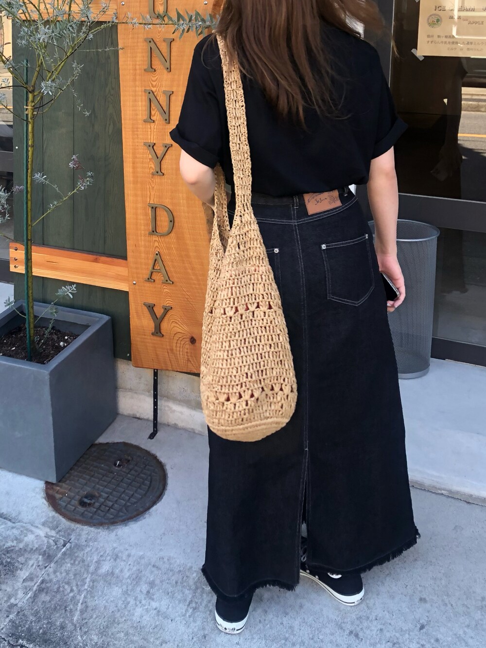 ベージュ系のかごバッグ、ブラック系のTシャツ/カットソー、ブラック系のデニムスカートを着用したレディースの秋コーディネートの3枚目の写真