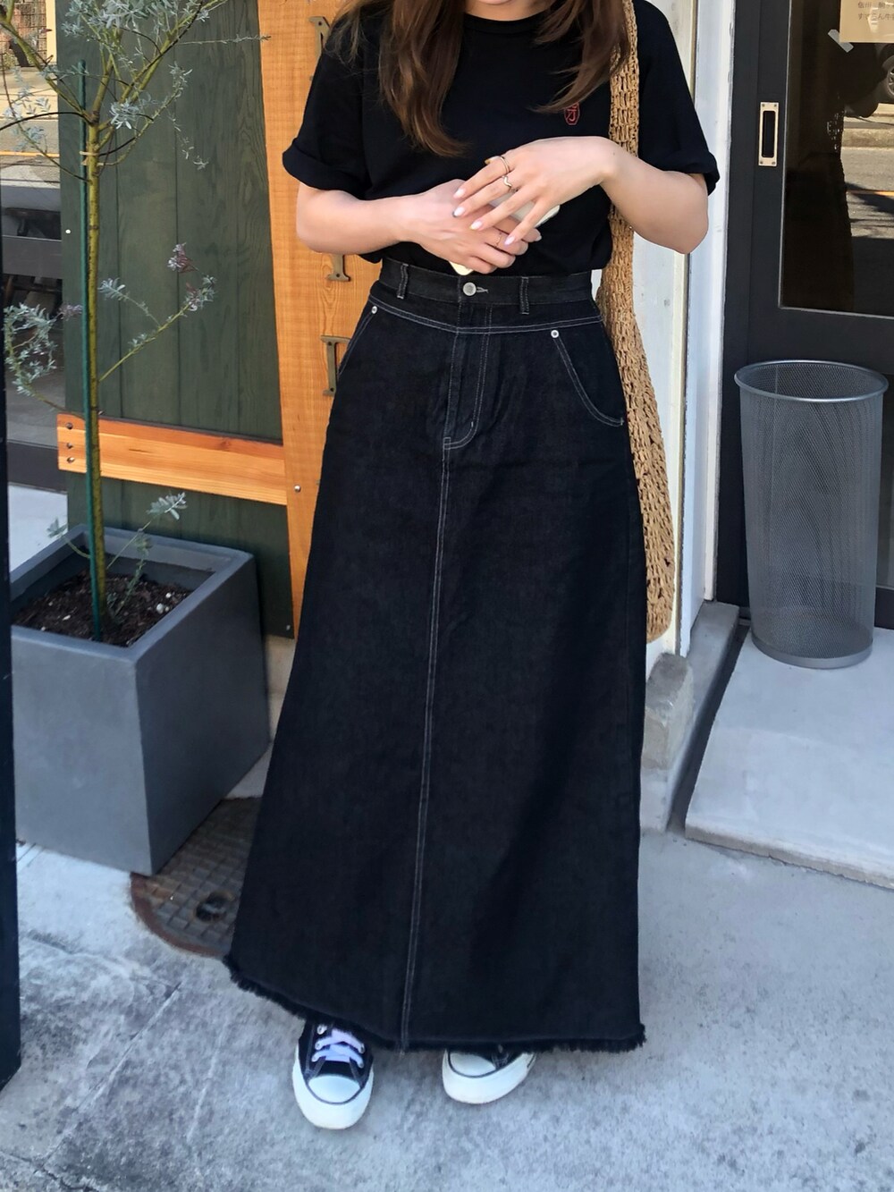 ベージュ系のかごバッグ、ブラック系のTシャツ/カットソー、ブラック系のデニムスカートを着用したレディースの秋コーディネートの2枚目の写真