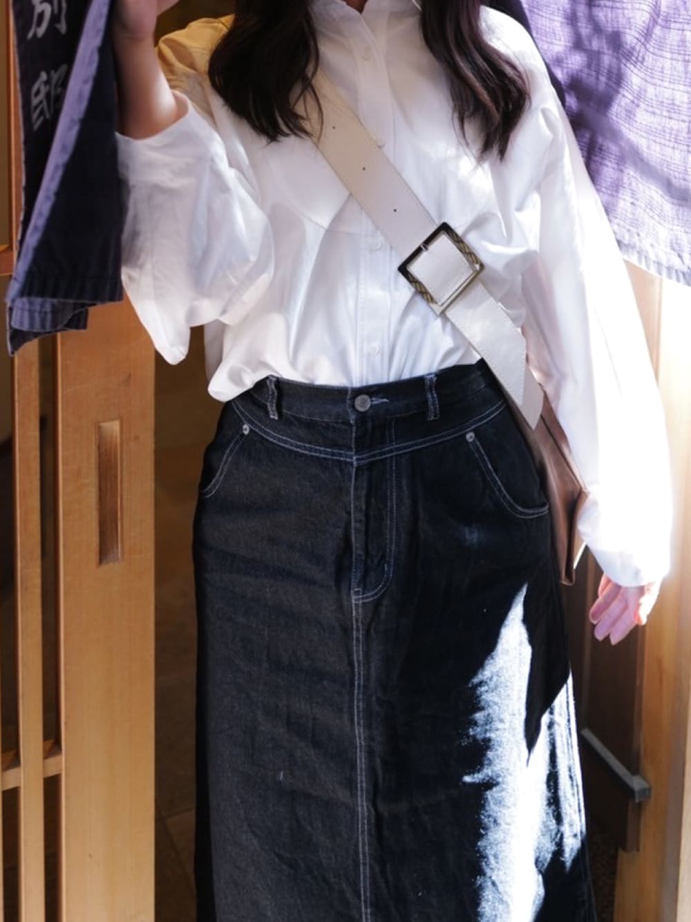 ブラック系のデニムスカート、ホワイト系のシャツ/ブラウス、ブラウン系のショルダーバッグを着用したレディースの秋コーディネートの2枚目の写真