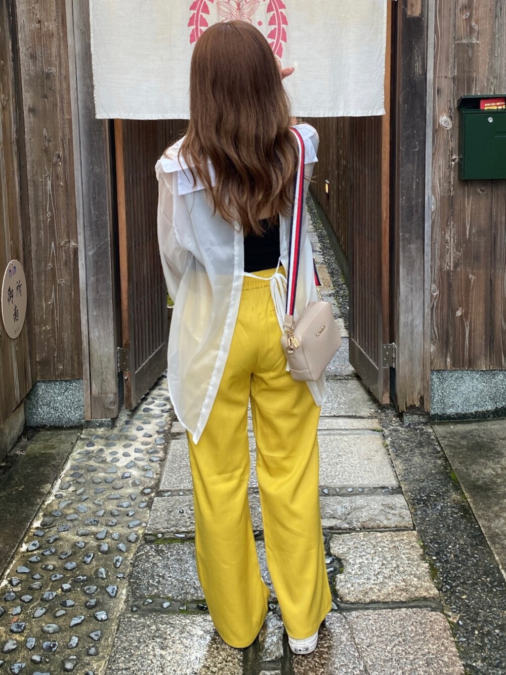 イエロー系のスラックス、ホワイト系のシャツ/ブラウス、ブラック系のタンクトップを着用したレディースの夏コーディネートの2枚目の写真