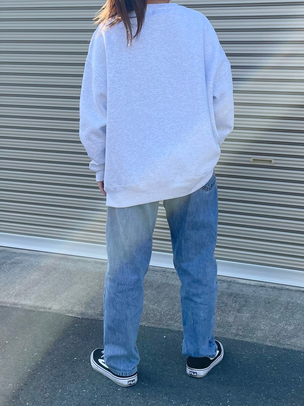 ホワイト系のスウェット、ブルー系のデニムパンツ、ブラック系のスニーカーを着用したレディースの春コーディネートの2枚目の写真