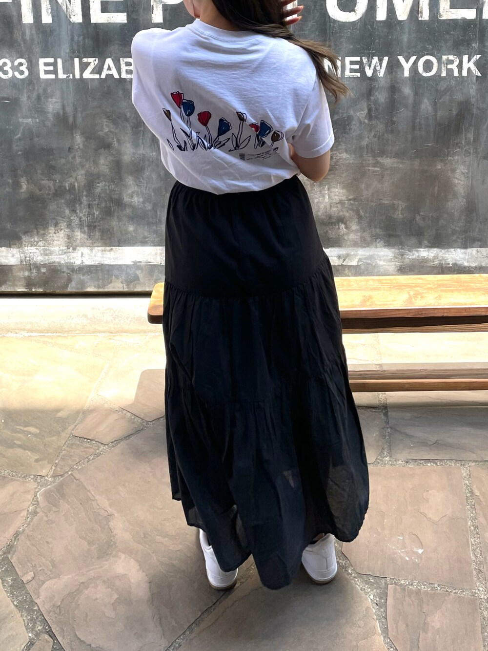 ホワイト系のスニーカー、ブラック系のスカート、ホワイト系のTシャツ/カットソーを着用したレディースの春コーディネートの3枚目の写真