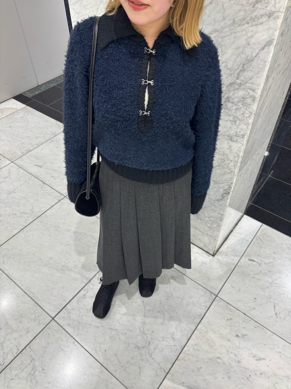 グレー系のスカート、ブルー系のニット/セーター、ブラック系のショルダーバッグを着用したレディースの秋コーディネートの3枚目の写真