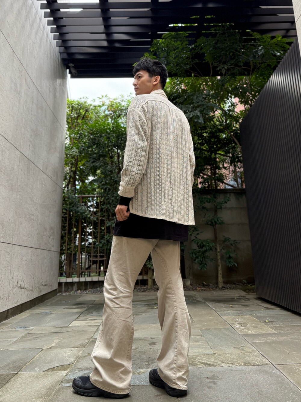 ホワイト系のニット/セーター、ブラック系のTシャツ/カットソー、ベージュ系のデニムパンツを着用したメンズの秋コーディネートの3枚目の写真