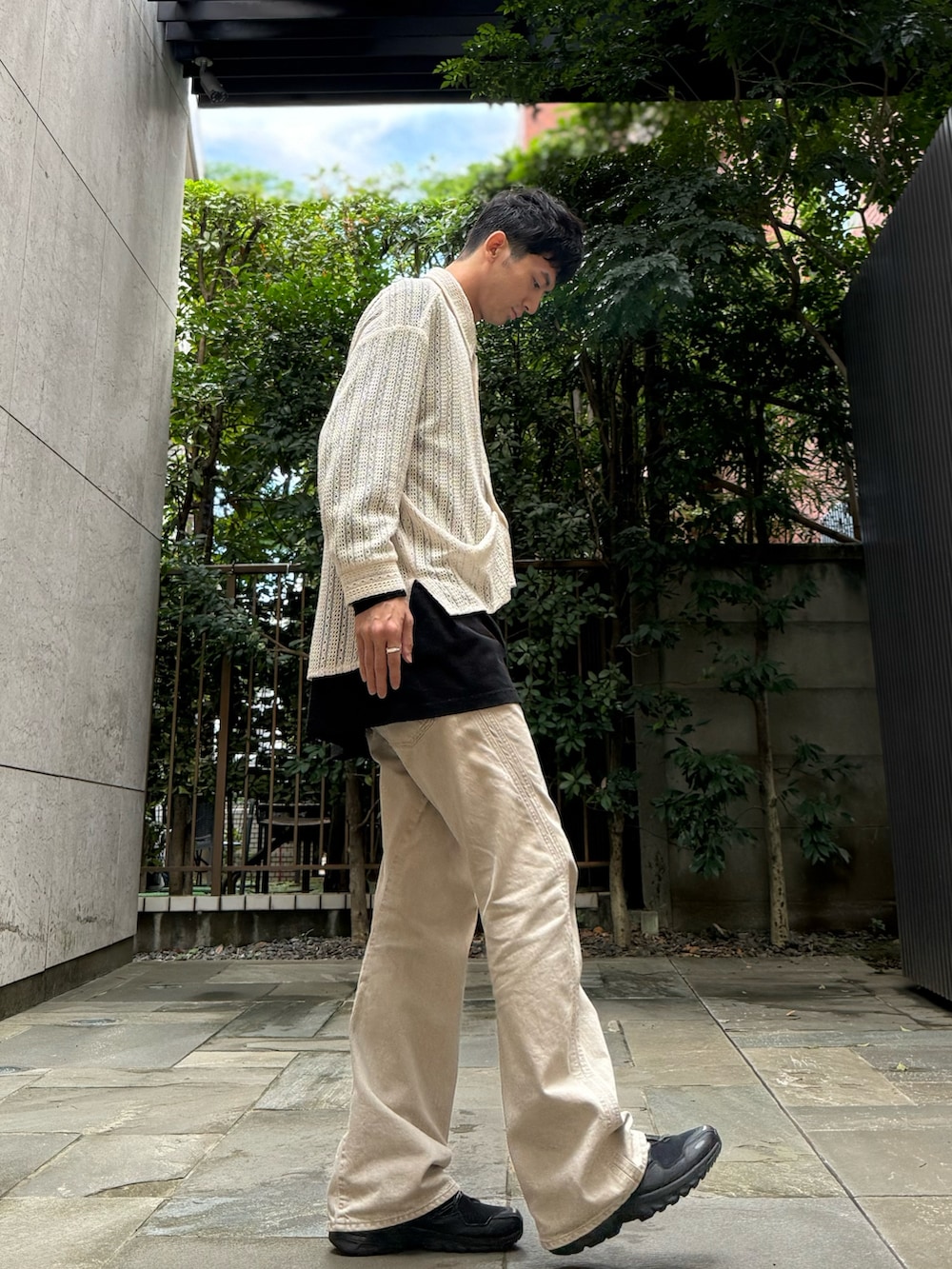 ホワイト系のニット/セーター、ブラック系のTシャツ/カットソー、ベージュ系のデニムパンツを着用したメンズの秋コーディネートの2枚目の写真