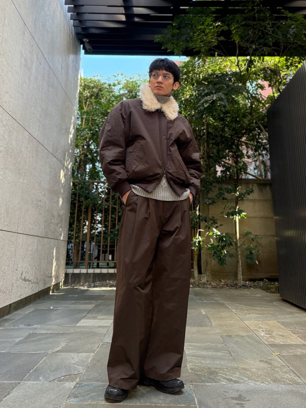 ブラウン系のブルゾン、ブラウン系のスラックス、ブラック系のスニーカーを着用したメンズの冬コーディネートの2枚目の写真