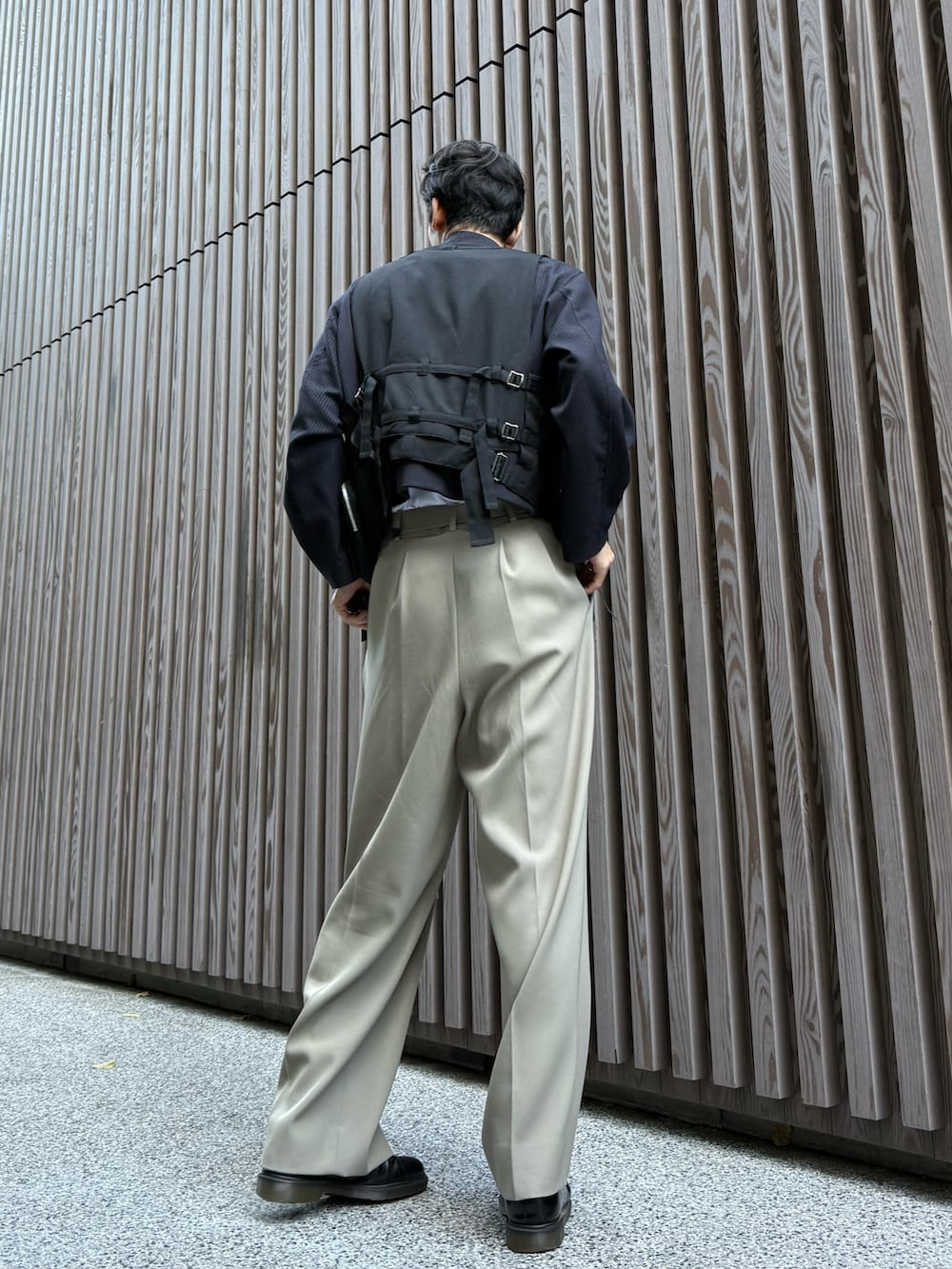 ブラック系のベスト、ベージュ系のスラックス、ブラック系のドレスシューズを着用したメンズの秋コーディネートの2枚目の写真