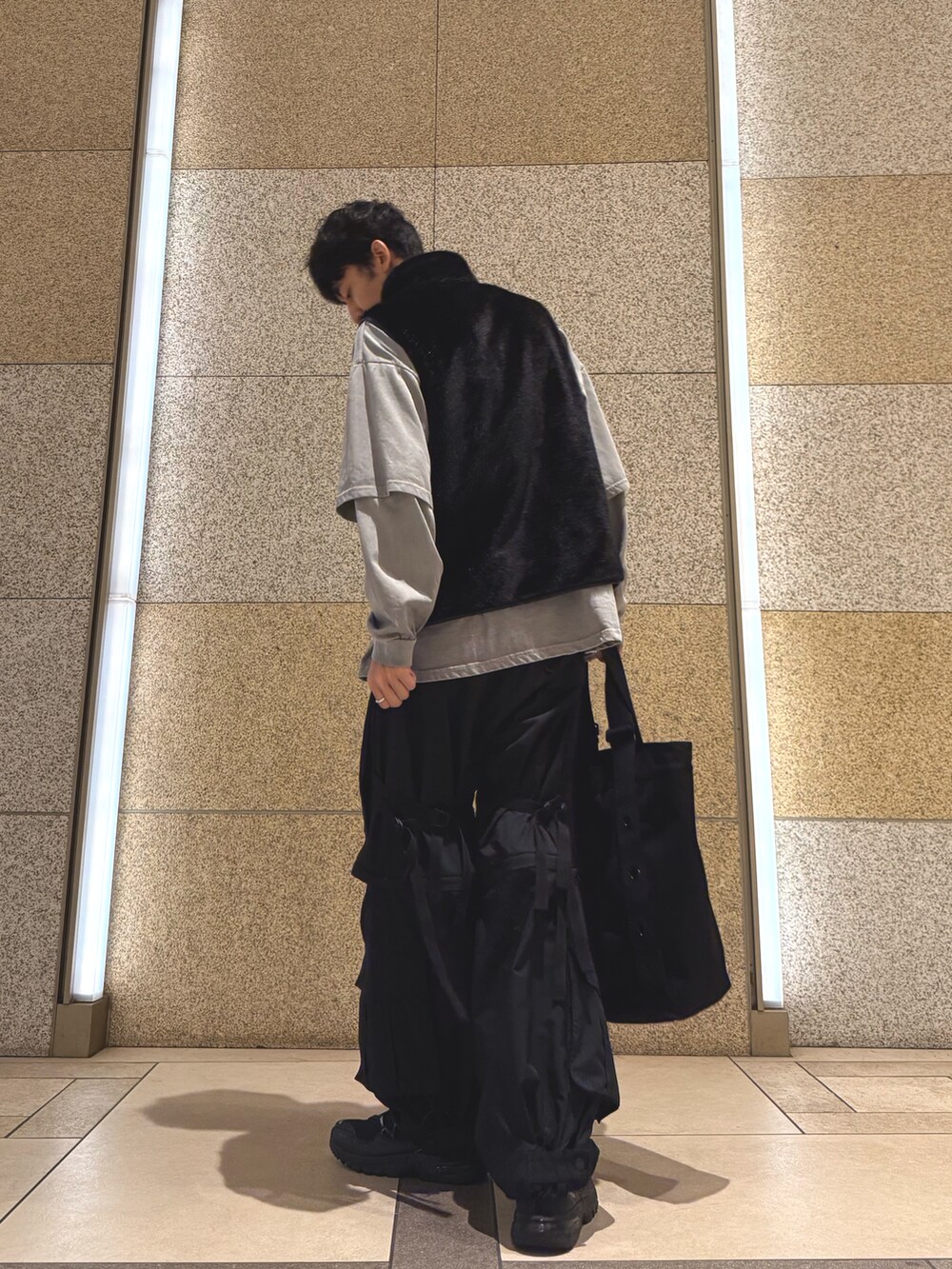 ブラック系のベスト、グレー系のTシャツ/カットソー、ブラック系のトートバッグを着用したメンズの秋コーディネートの3枚目の写真