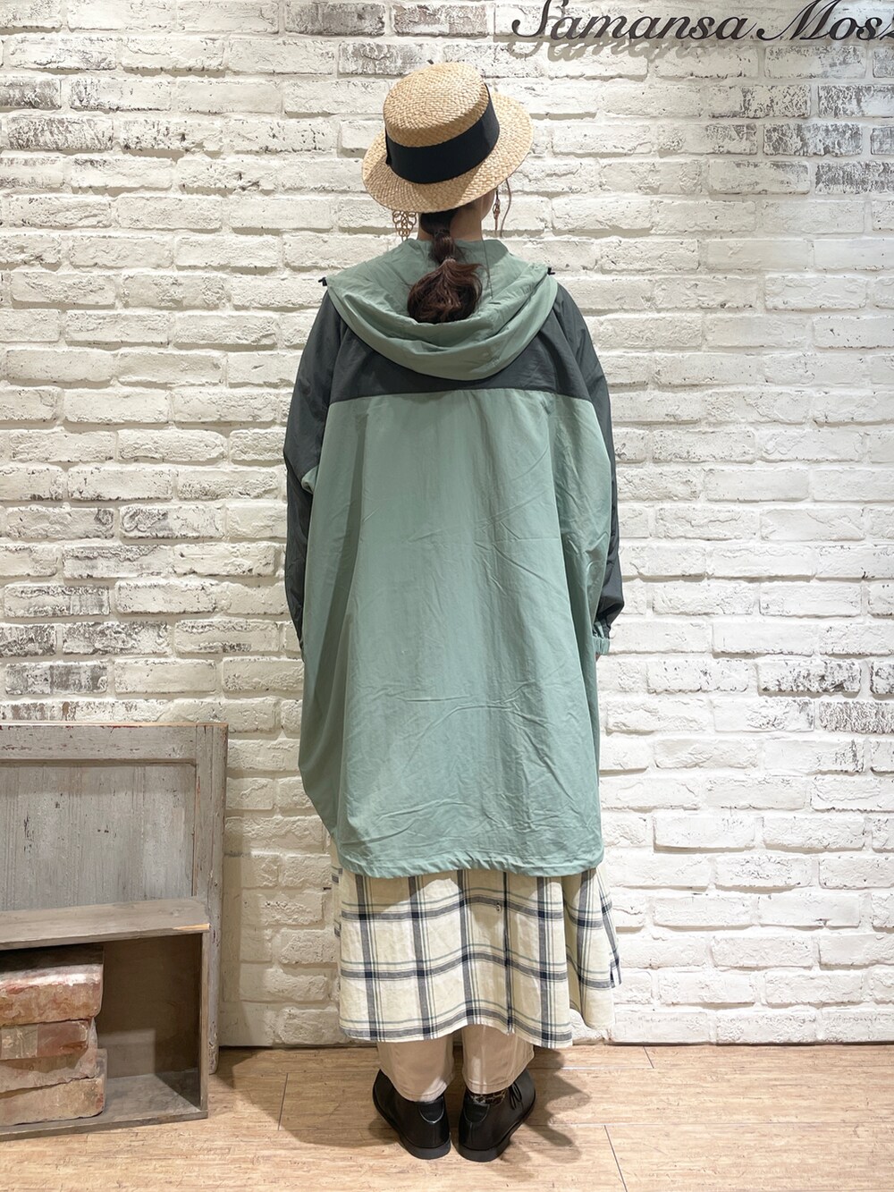 イエロー系のワンピース、グリーン系のマウンテンパーカー、ベージュ系のデニムパンツを着用したレディースの春コーディネートの3枚目の写真