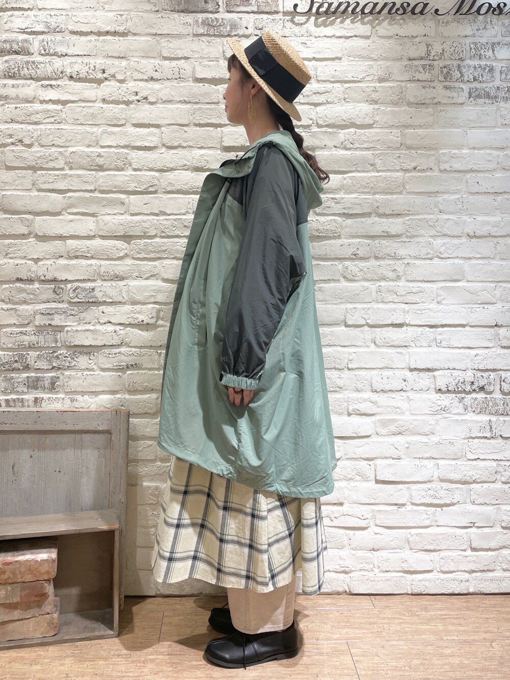 イエロー系のワンピース、グリーン系のマウンテンパーカー、ベージュ系のデニムパンツを着用したレディースの春コーディネートの2枚目の写真