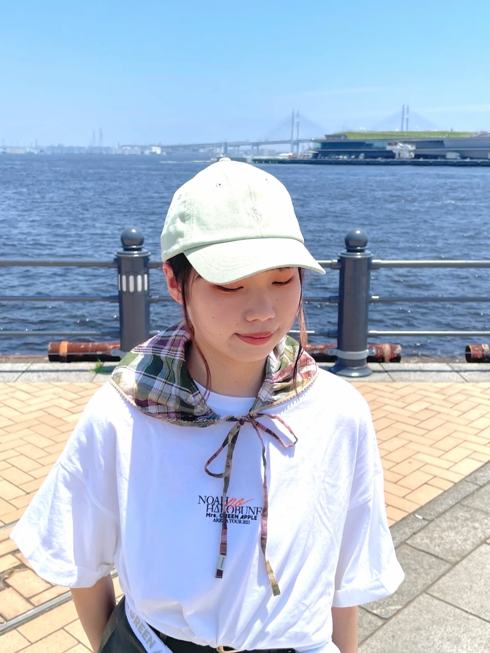 グリーン系のチノパンツ、ホワイト系のサンダル、グリーン系のキャップを着用したレディースの夏コーディネートの3枚目の写真